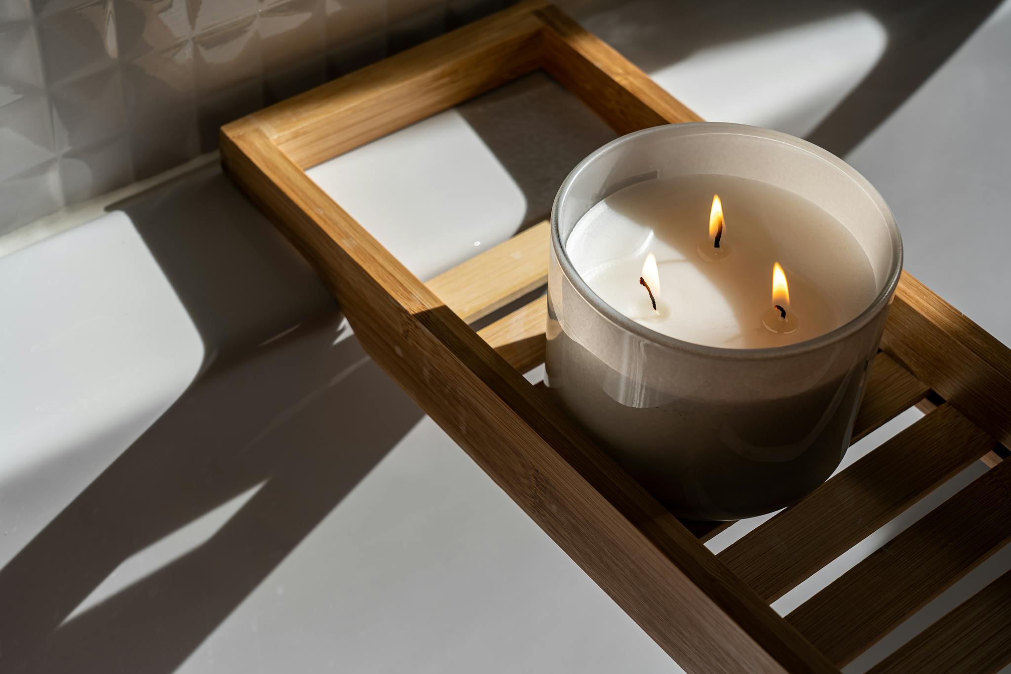 A minimalist setting with a lit candle on a wooden tray, casting warm shadows and creating a soothing ambiance.