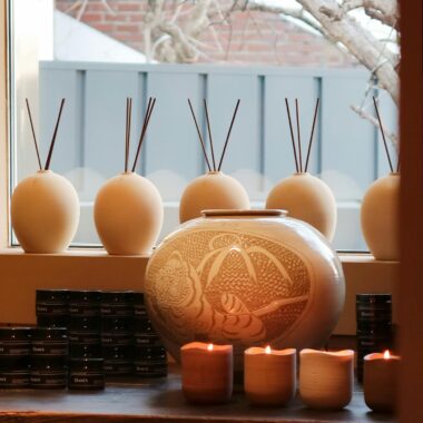 A serene indoor display of aromatherapy candles and diffusers on a wooden table by a window.