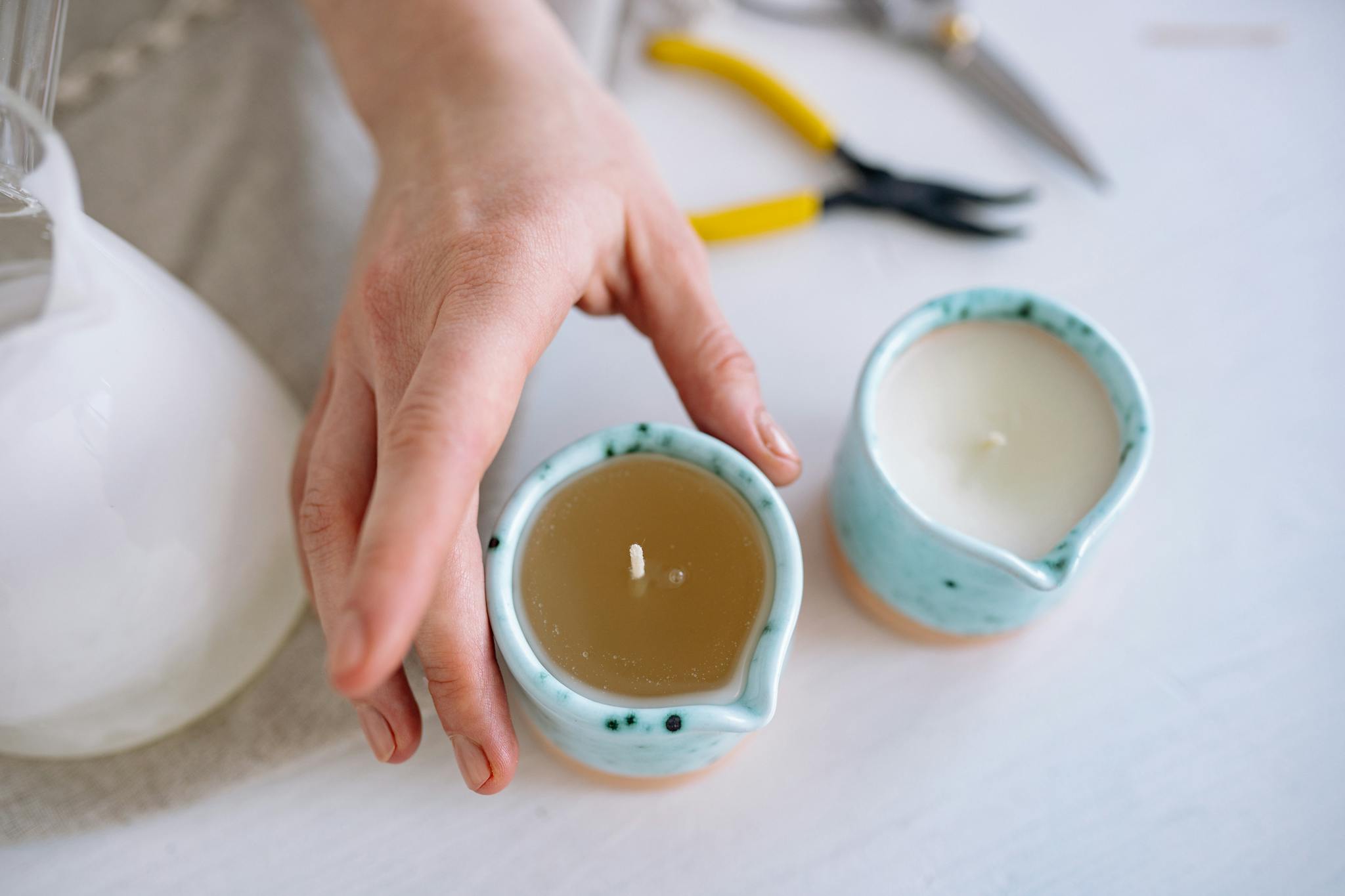Close-up of a person arranging ceramic candles in a cozy setting.